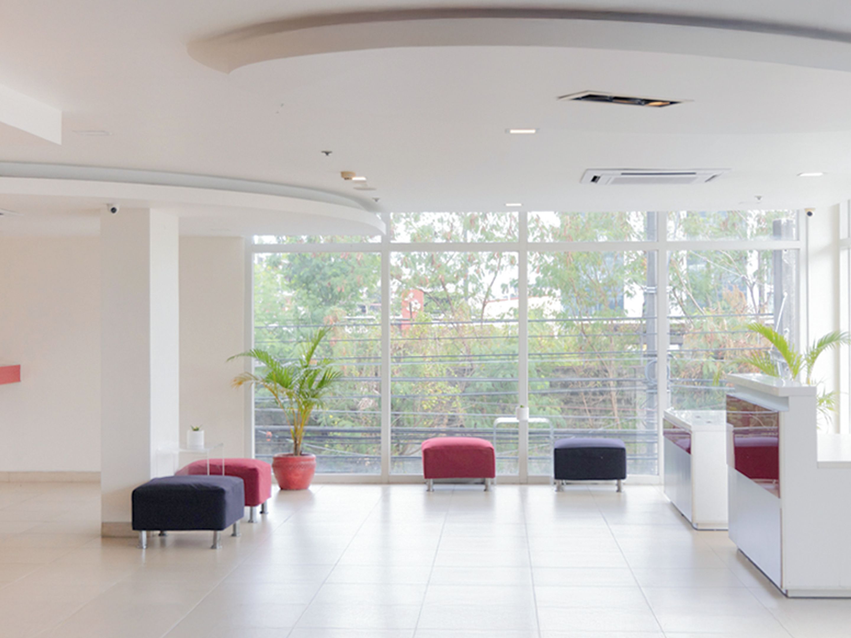 Un hall d’entrée spacieux avec une grande fenêtre, un comptoir d’accueil et des espaces où s’asseoir.