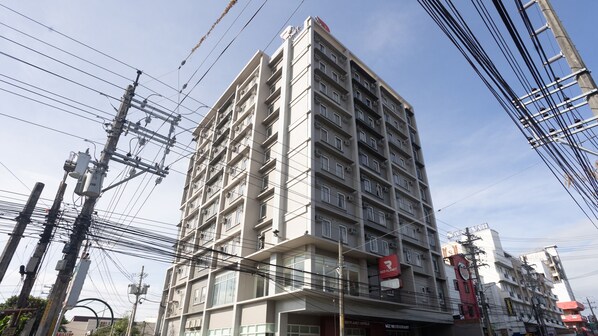 Un hôtel à plusieurs étages au design moderne, doté de balcons et d’une enseigne Red Planet bien visible.