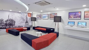 A modern lobby with seating areas, a large mural, and multiple screens. - Red Planet Manila Malate Mabini (Manila)