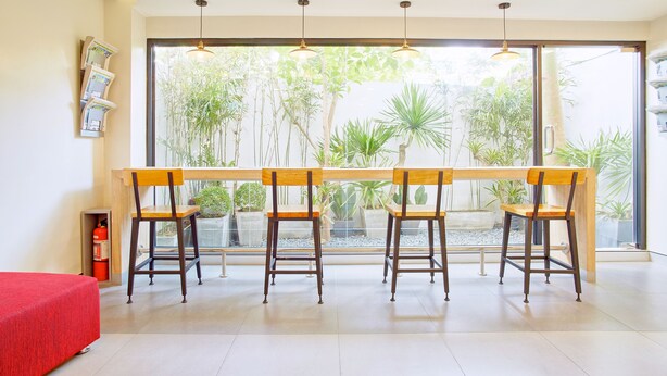 A room with a long wooden table and four wooden chairs, a red bed, and a fire extinguisher. - Red Planet Manila Malate Mabini (Manila)