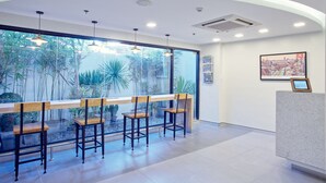 A reception area with a curved ceiling, a reception desk, and a large window with a view of indoor plants. - Red Planet Manila Malate Mabini (Manila)