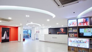 A modern reception area with a red and white color scheme, a reception desk labeled 'MABINI', and a digital display board with various information. - Red Planet Manila Malate Mabini (Manila)