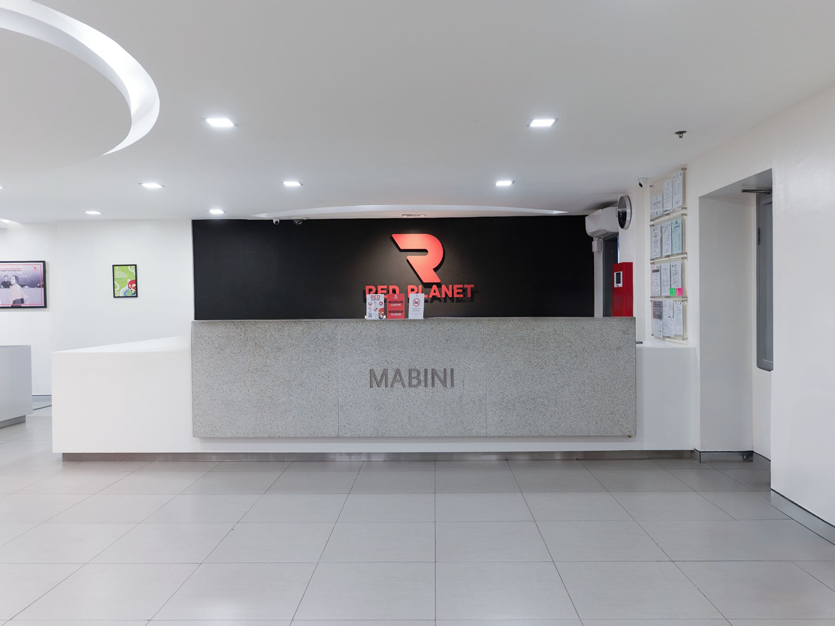 A reception desk with a logo, a nameplate, and a bulletin board.
