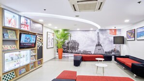 A modern lobby with a reception desk, seating areas, and a display of books and magazines. - Red Planet Manila Malate Mabini (Manila)
