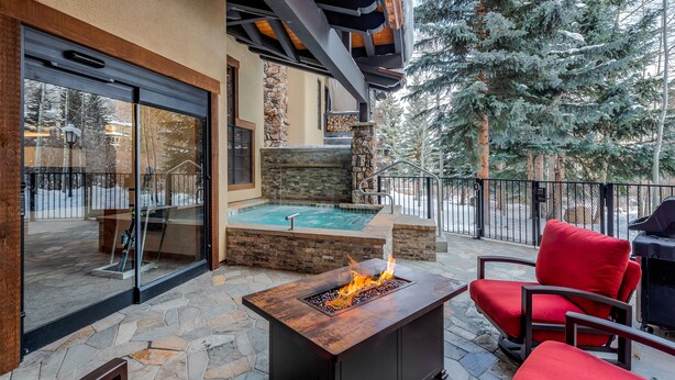 An outdoor patio with a stone floor, a fire feature, and red seating.