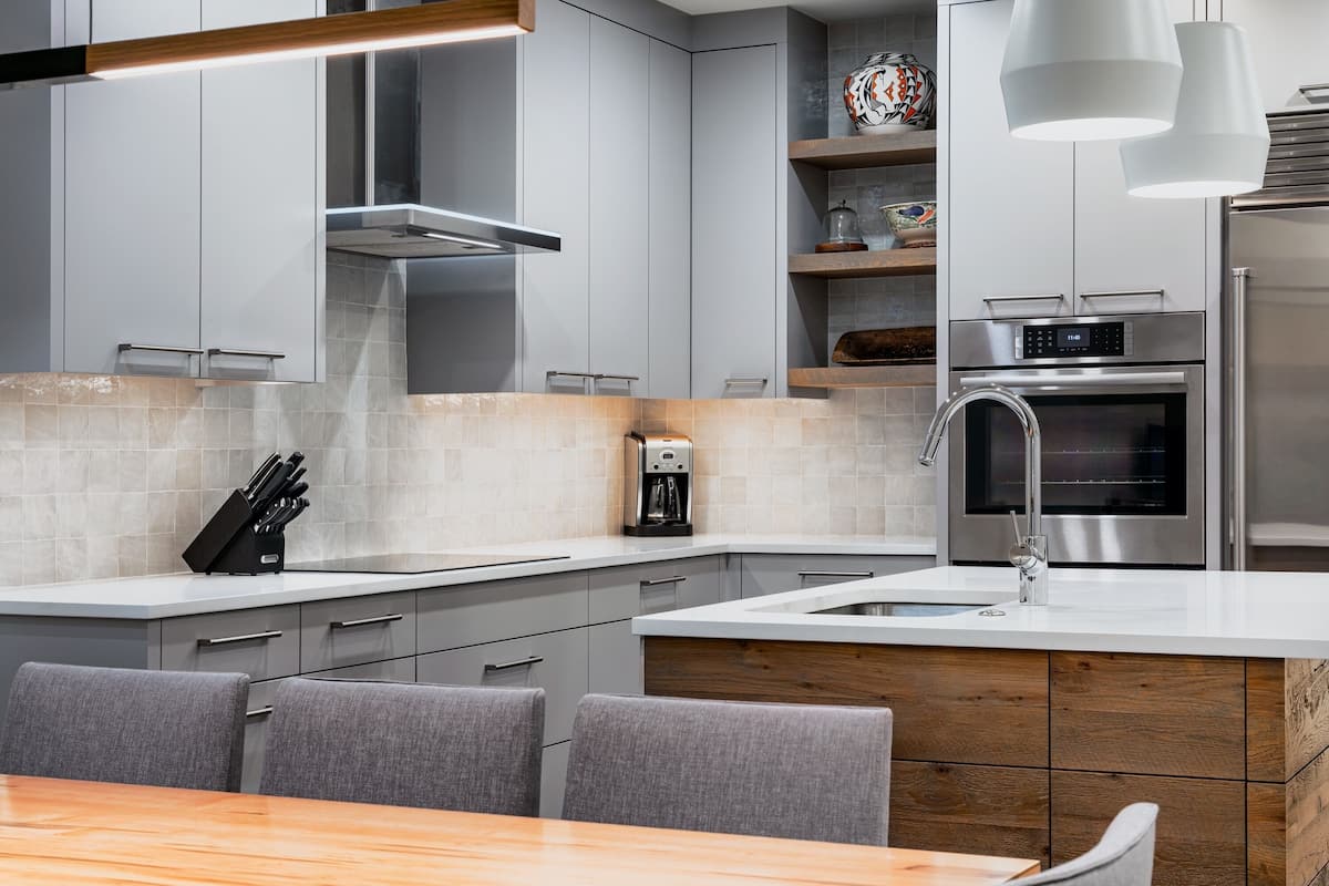 A modern kitchen with grey cabinetry, a stainless steel oven, and a coffee maker.