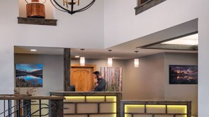 A spacious lobby with a reception desk, comfortable seating, a chandelier, and artwork on the walls.