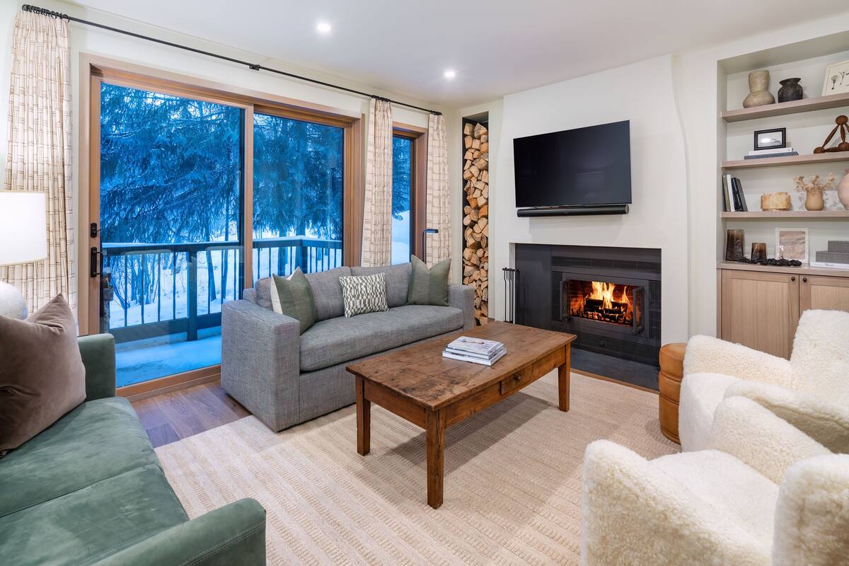 A living room with a fireplace, a sofa, a coffee table, and a TV.