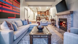 A modern living room with a sectional sofa, a coffee table, and a fireplace.