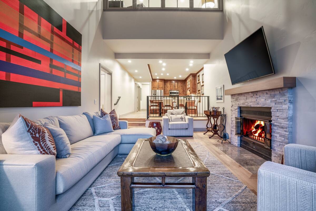 A modern living room with a sectional sofa, a coffee table, and a fireplace.
