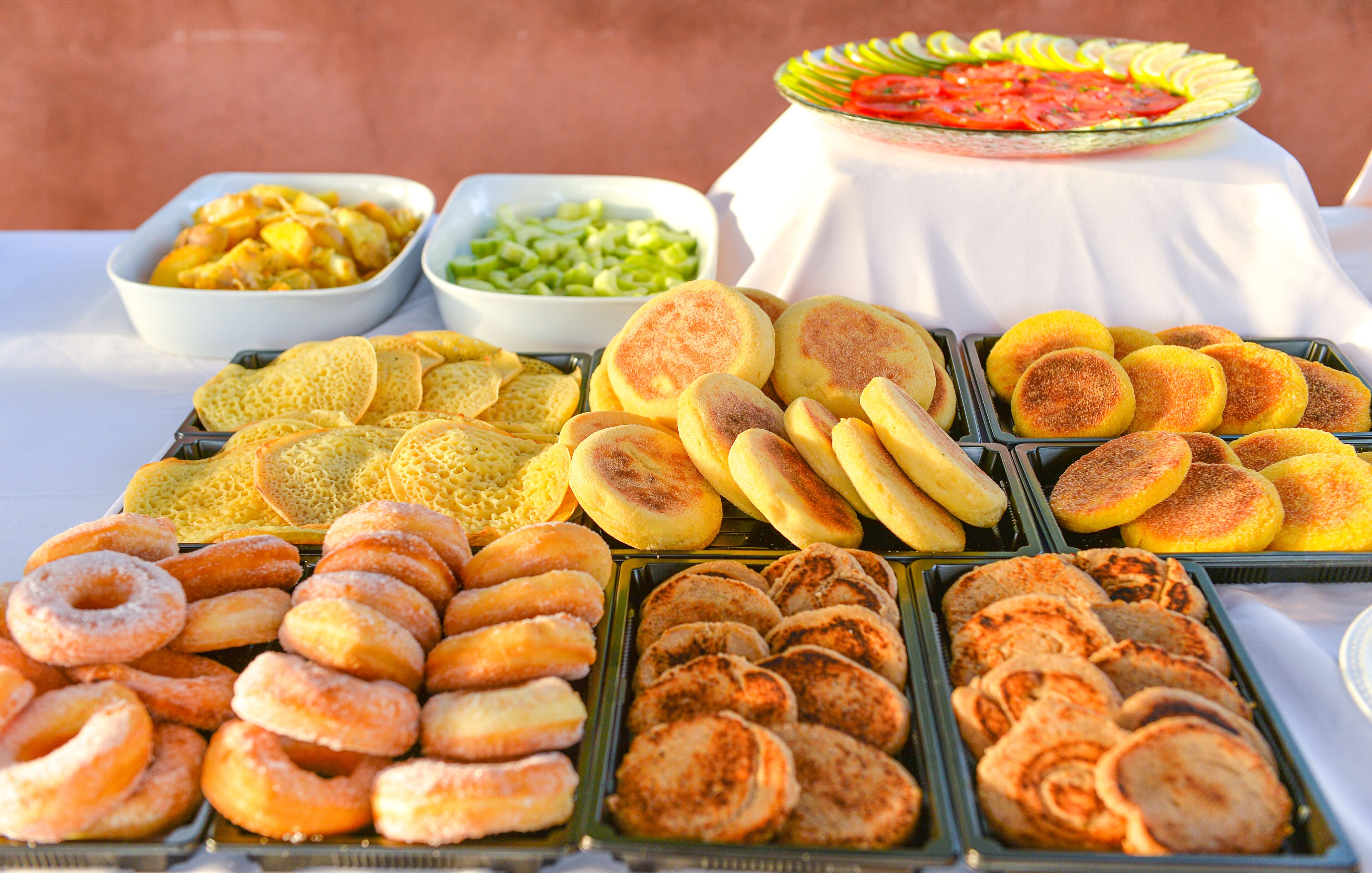 A buffet table with various baked goods and side dishes.