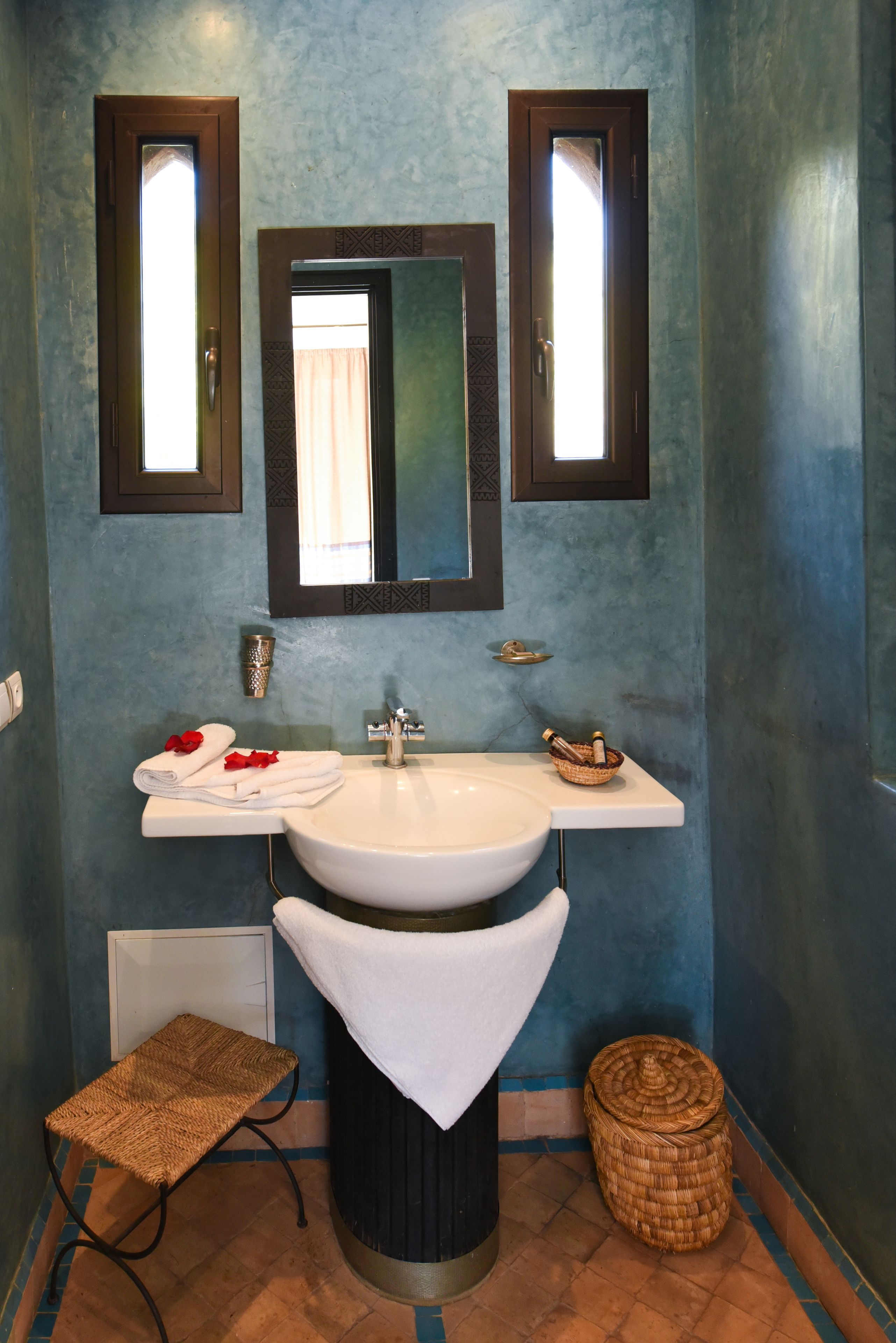 A bathroom with a sink, mirror, towel rack, and a small wicker basket.