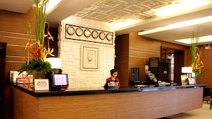 A hotel reception desk with a wooden counter, a clock, and a framed picture on the wall. - Manila Grand Opera Hotel (Manila)
