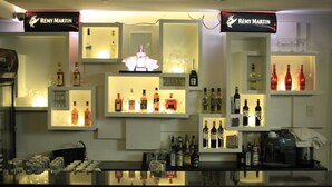 A bar area with shelves displaying various bottles and glasses, illuminated by overhead lighting. - Manila Grand Opera Hotel (Manila)