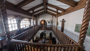 Un interior espacioso con techo alto, vigas de madera y una escalera central.
