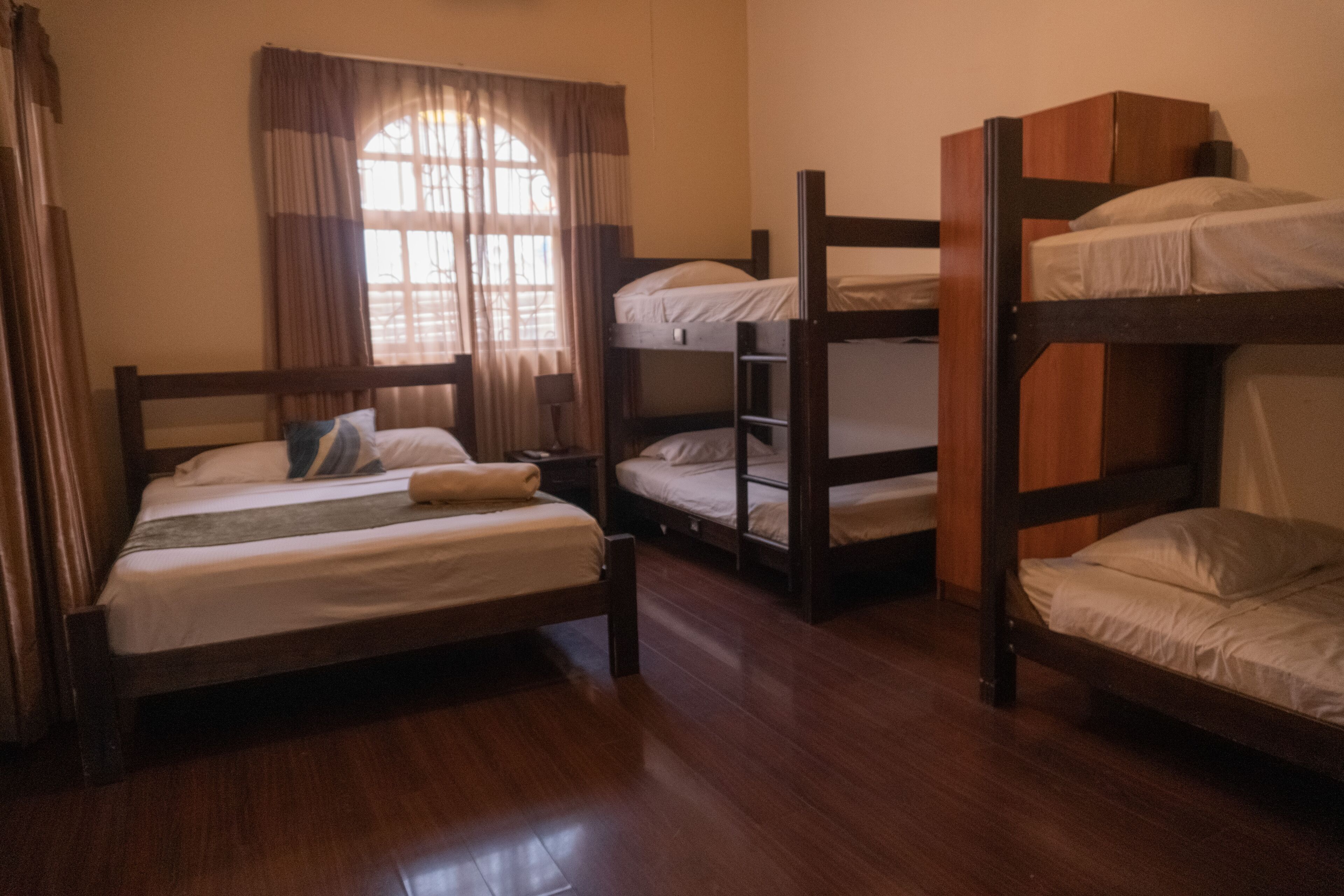 Une chambre avec un lit simple, un lit superposé et une fenêtre avec des rideaux.