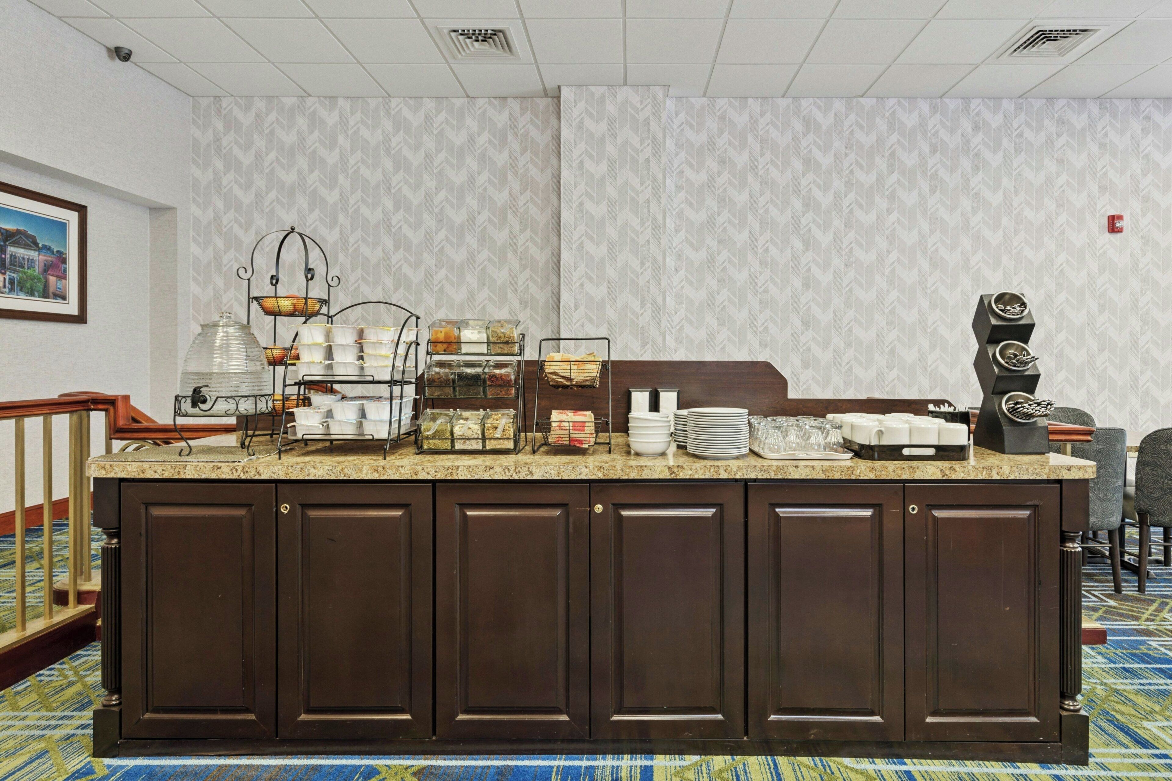 A hotel reception area with a buffet counter, a coffee machine, and a framed picture on the wall.