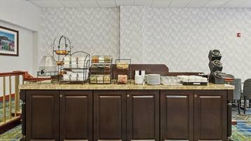 A hotel reception area with a buffet counter, a coffee machine, and a framed picture on the wall.
