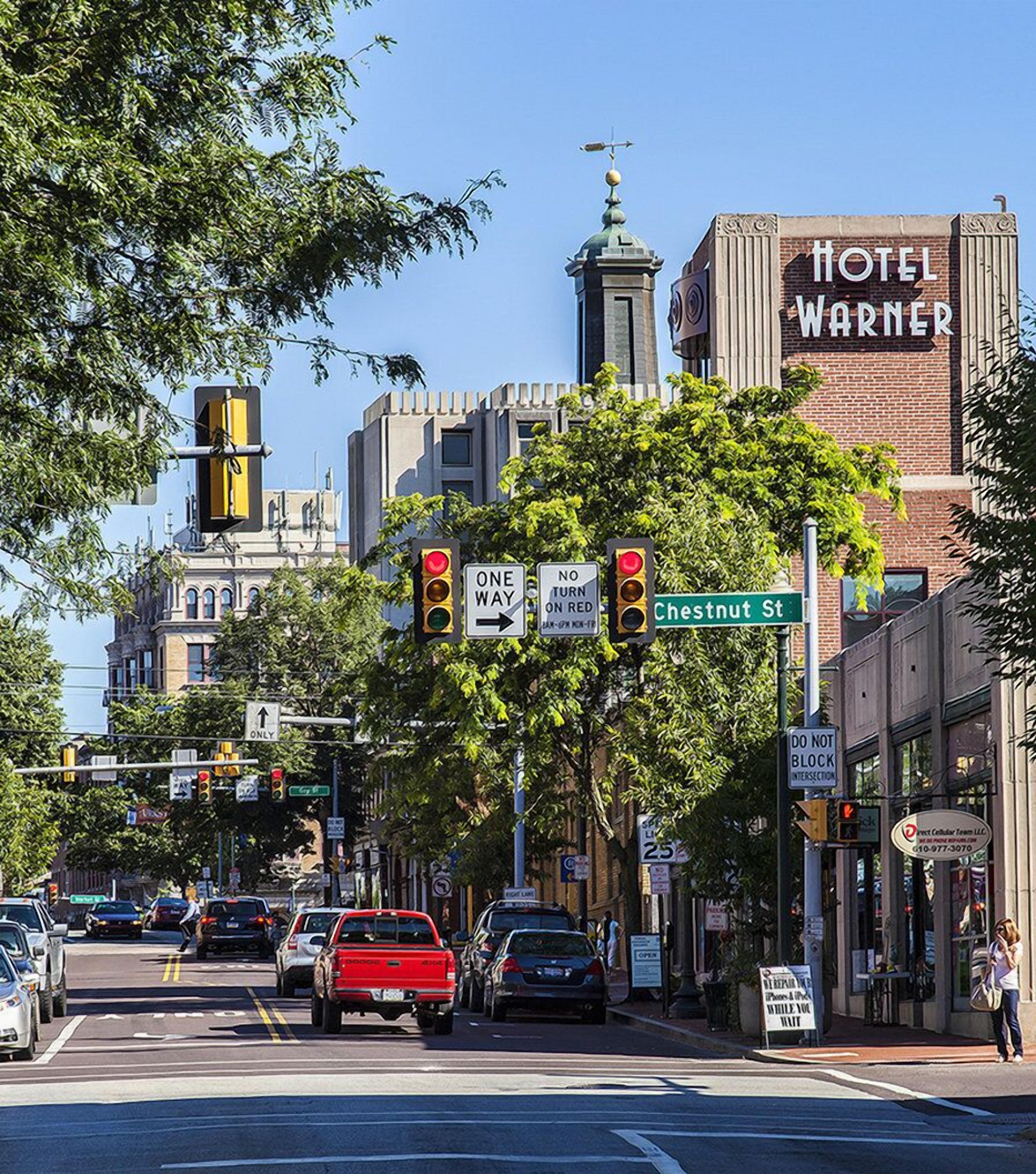 A street intersection with traffic lights, street signs, and a hotel named 'Hotel Warner' in the background.