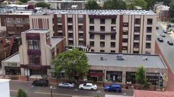 Un hotel de varios pisos con entrada central, múltiples plantas y un estacionamiento con coches.