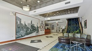 Vestíbulo de hotel con mostrador de recepción, zona de estar y un mural grande en la pared.