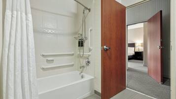 A bathroom with a bathtub, shower, and grab bars.
