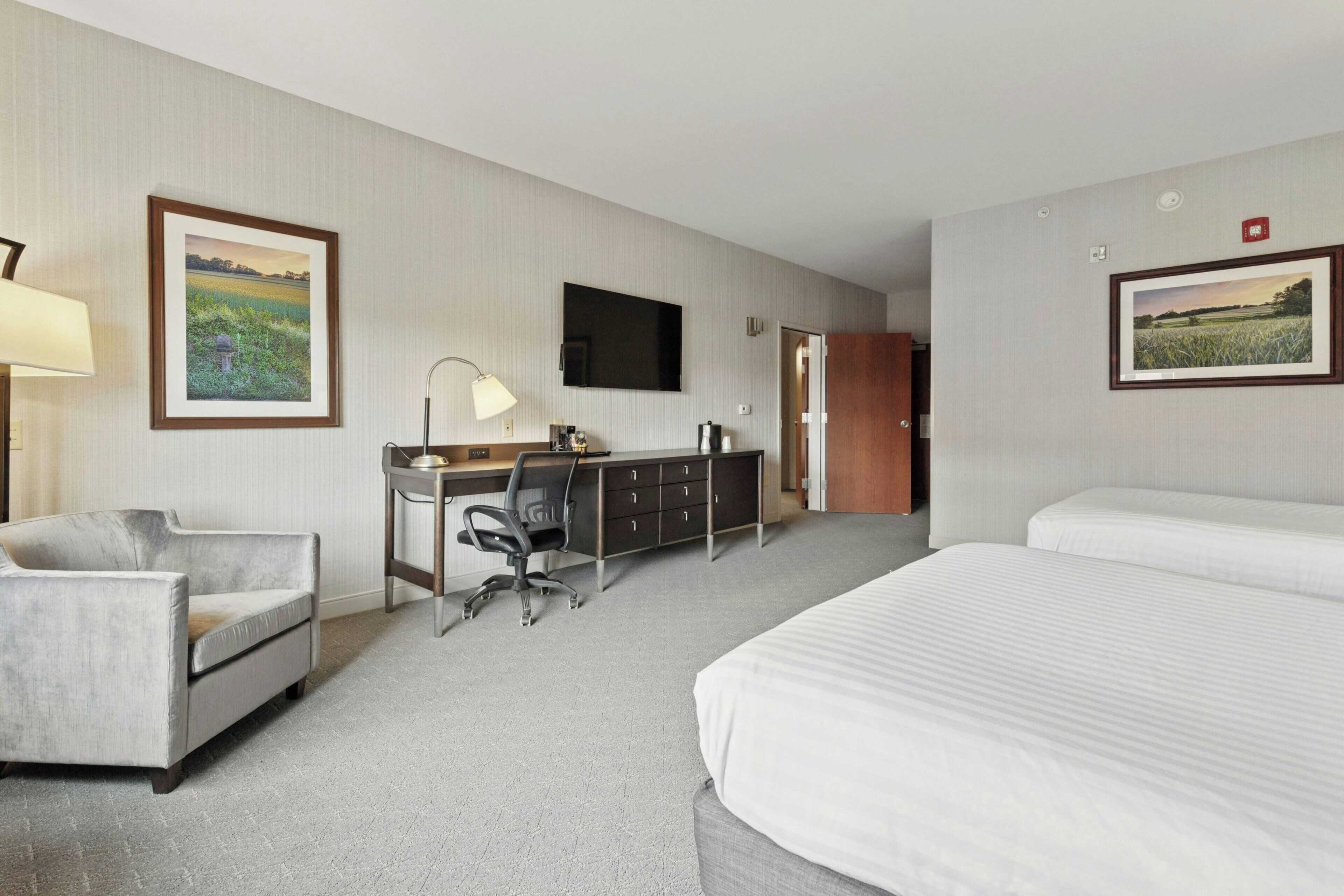 A hotel room with a bed, desk, chair, and a television.
