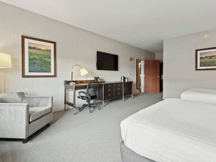 A hotel room with a bed, desk, chair, and a television.