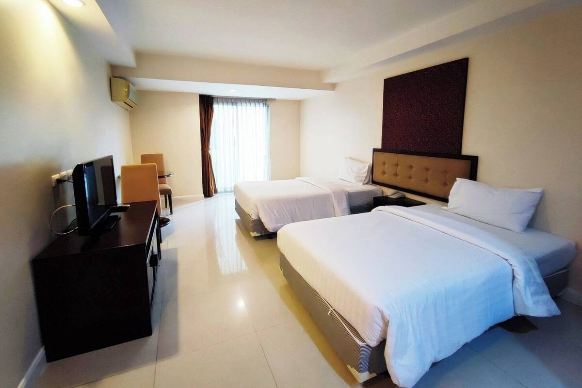 Een hotelkamer met twee bedden, een bureau met een computer, een stoel en een televisie.