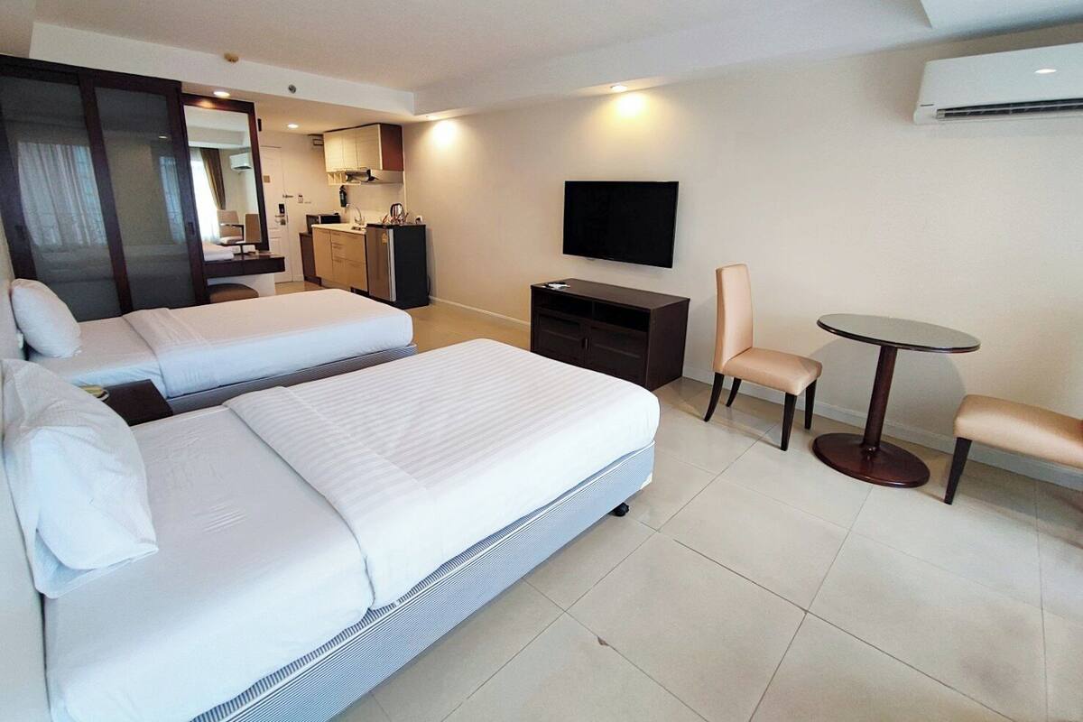 Een hotelkamer met twee bedden, een bureau, een stoel, een televisie en een tafeltje.