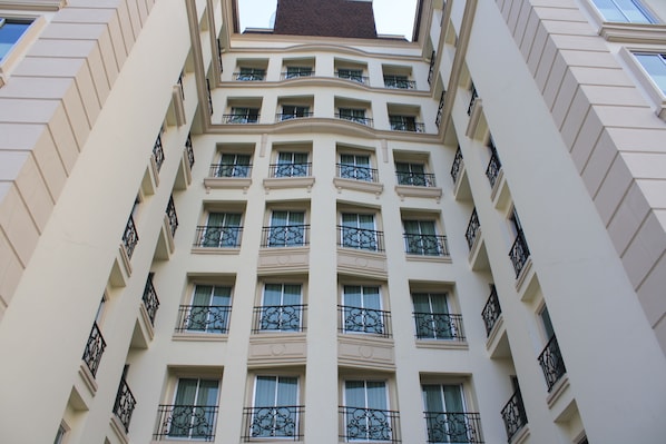 A multi-story building with a symmetrical facade, featuring evenly spaced windows and decorative iron railings on balconies.