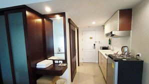 Una habitación de hotel compacta con kitchenette, baño pequeño y cama.