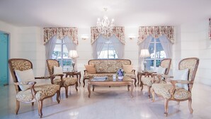 Un amplio salón con un conjunto de sofá, sillones a juego, una mesa de centro y una araña.