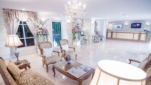 Un vestíbulo amplio con un mostrador de recepción, asientos cómodos y un candelabro.