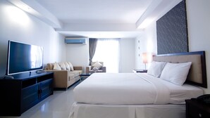 Una habitación de hotel moderna con una cama grande, un televisor de pantalla plana, un sofá y un escritorio.