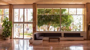 A spacious lobby with a large window, a seating area, and a potted plant. - Club Hotel Marazul (Adeje)