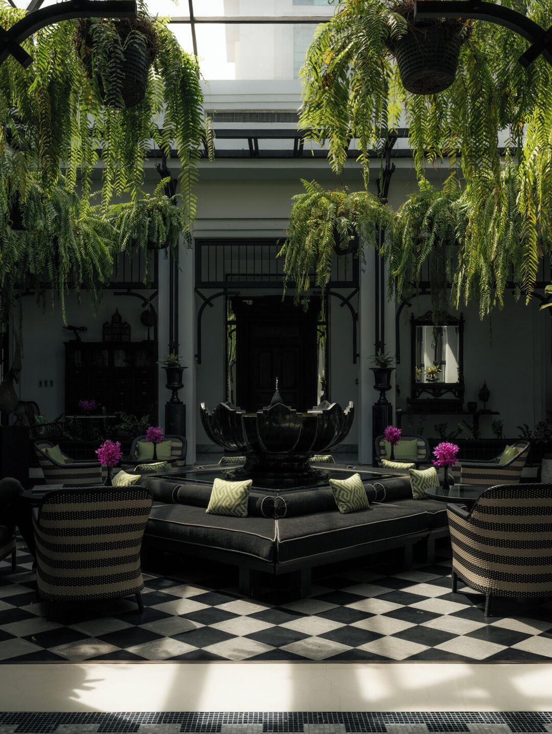 A luxurious indoor setting with a checkered floor, a central seating area with sofas and chairs, and hanging plants.