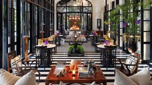 A spacious lobby with a high ceiling, large windows, and a central seating area with a coffee table. - The Siam (Bangkok)