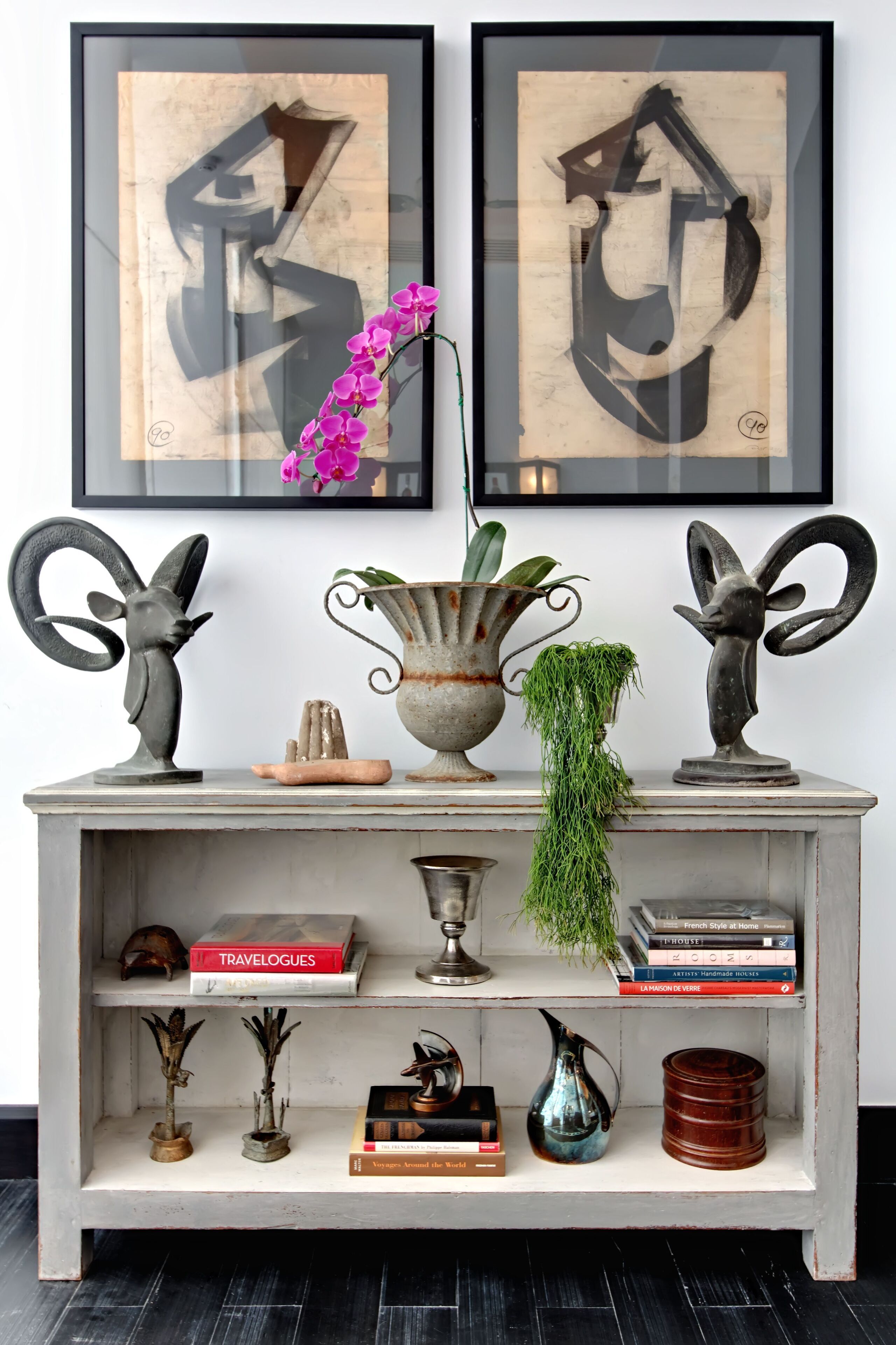 A shelf with decorative items, books, and framed artwork.