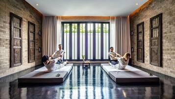 A room with brick walls, large windows, and two massage tables.