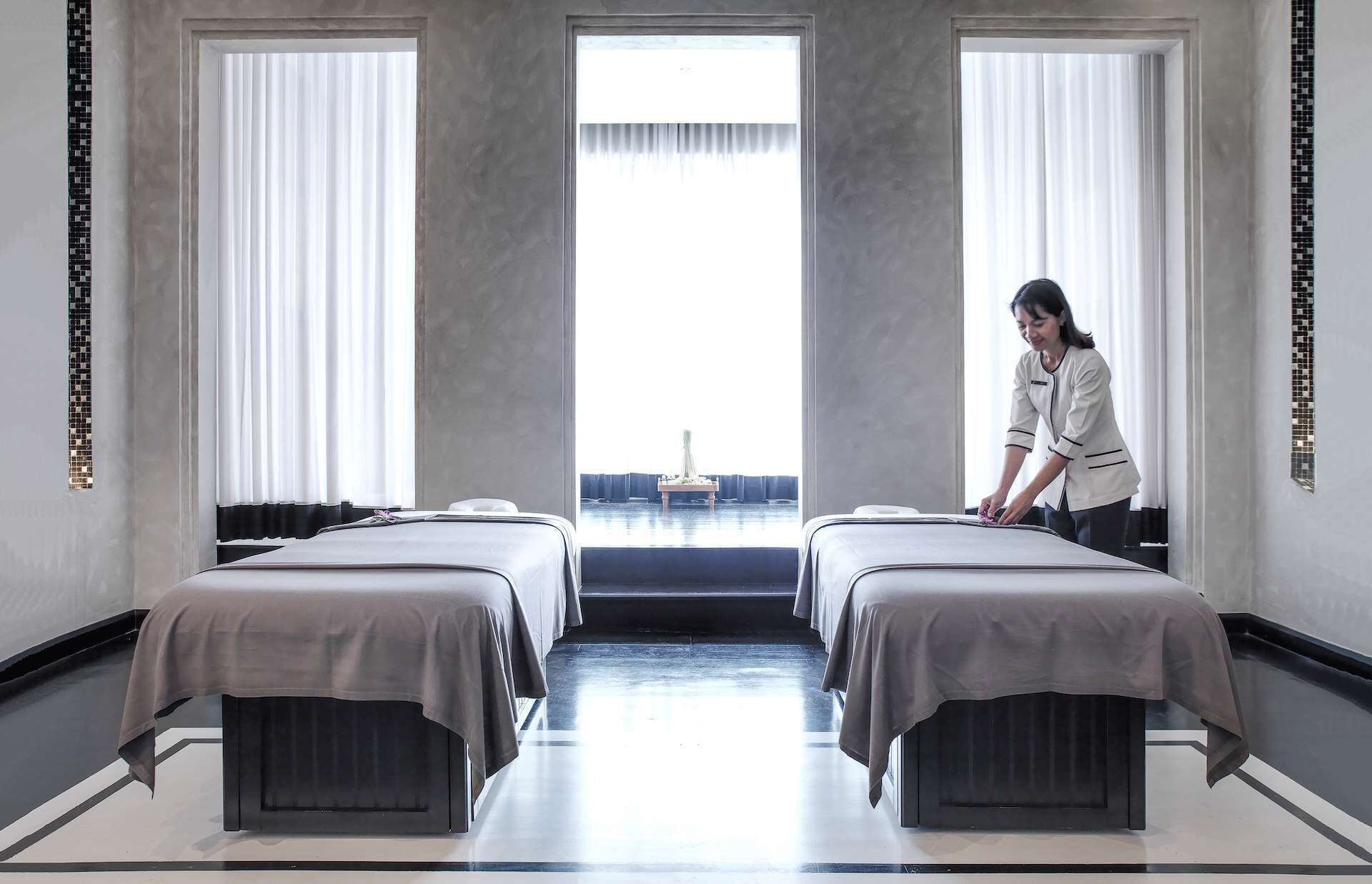 A hotel room with two beds, a large window, and a view of the sea.