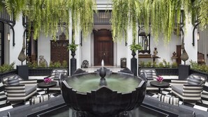 A lobby with a black and white checkered floor, a central fountain, and hanging ferns.