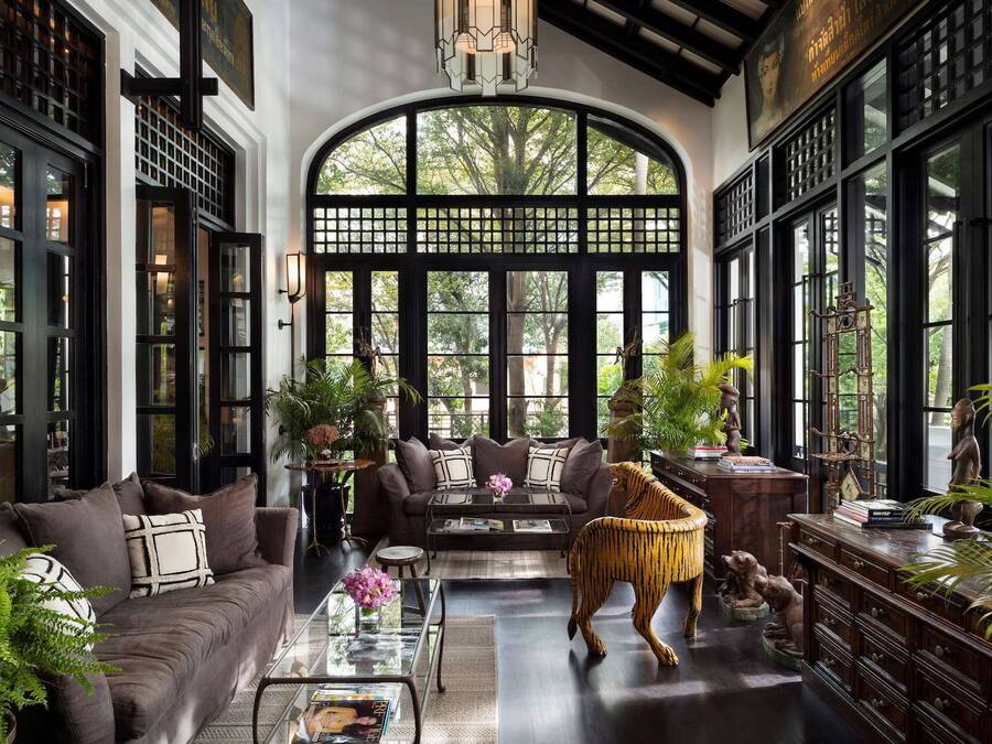 A spacious room with a large arched window, a sofa, a coffee table, and decorative items including a tiger statue.