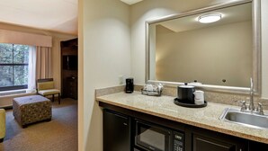 Une salle de bain d’hôtel équipée d’un grand miroir, d’un lavabo, d’une machine à café et d’un four à micro-ondes.