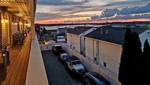 A view from a balcony overlooking a parking area with several cars, a building with a sloped roof, and a sunset in the background. - Regal Inn (Hampton)