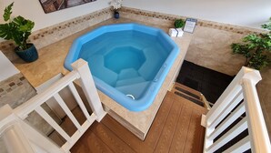 A hot tub in a room with a wooden floor, a white railing, and a painting of a beach scene on the wall. - Regal Inn (Hampton)