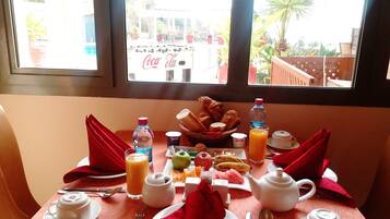 A breakfast table with a variety of food items, a bottle of water, and a teapot.