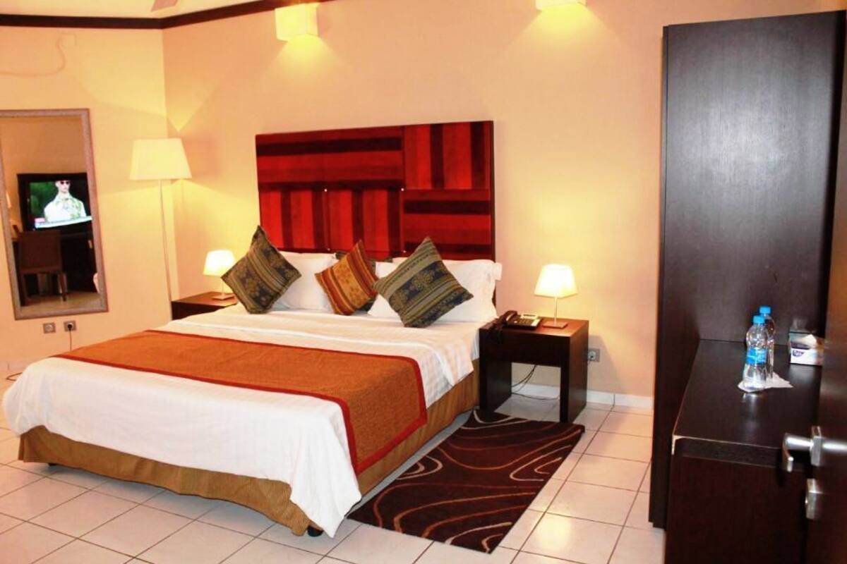 Ein Hotelzimmer mit einem großen Bett, zwei Nachttischen, einem Spiegel und einem Kleiderschrank.