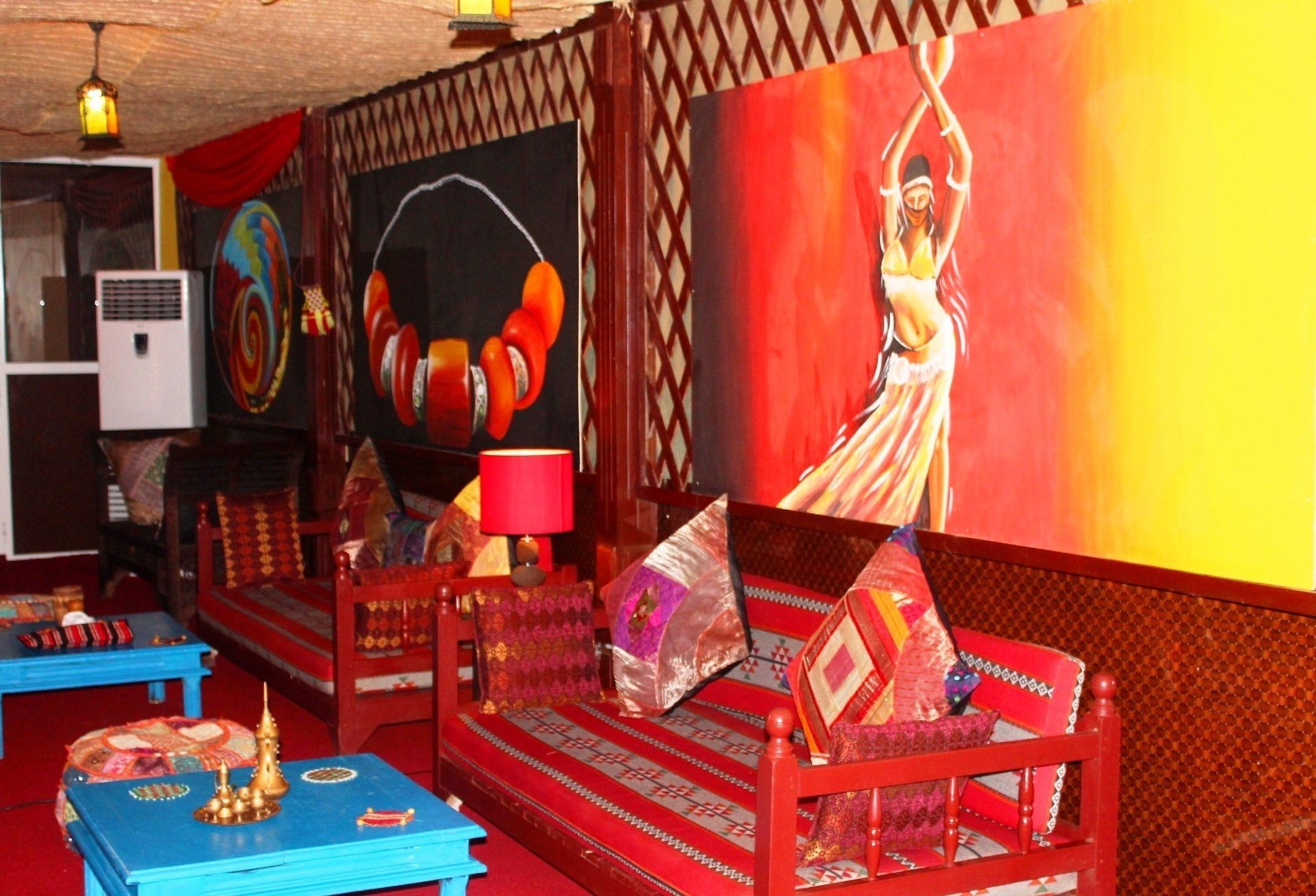 Una habitación con un sofá rojo, una mesa azul y un cuadro grande en la pared.