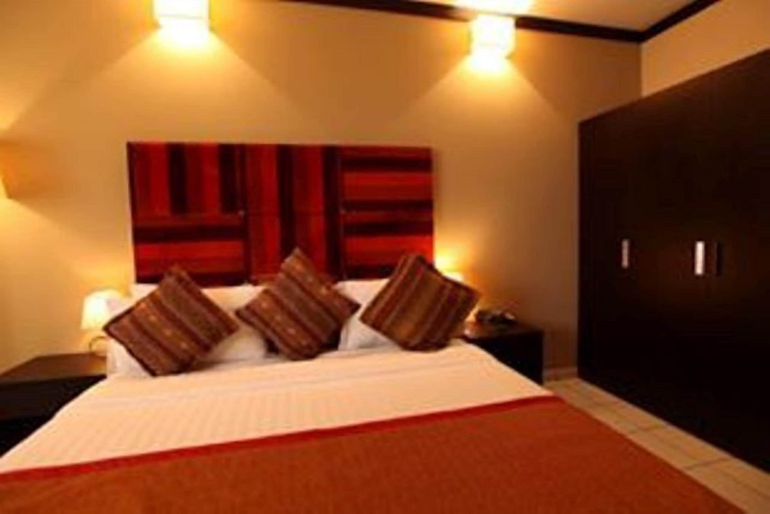 A hotel room with a bed, a nightstand, a wall-mounted TV, and a wardrobe.